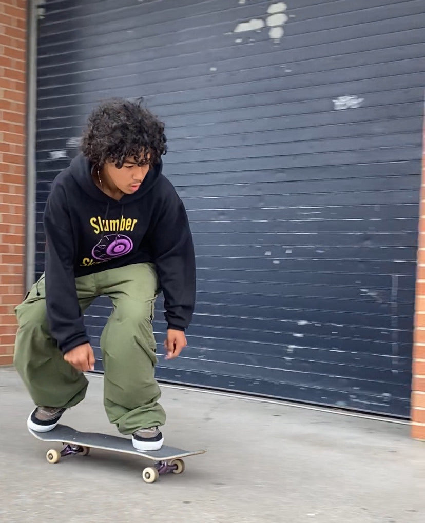 Slumber Skate Co. member riding a skateboard near industrial garage